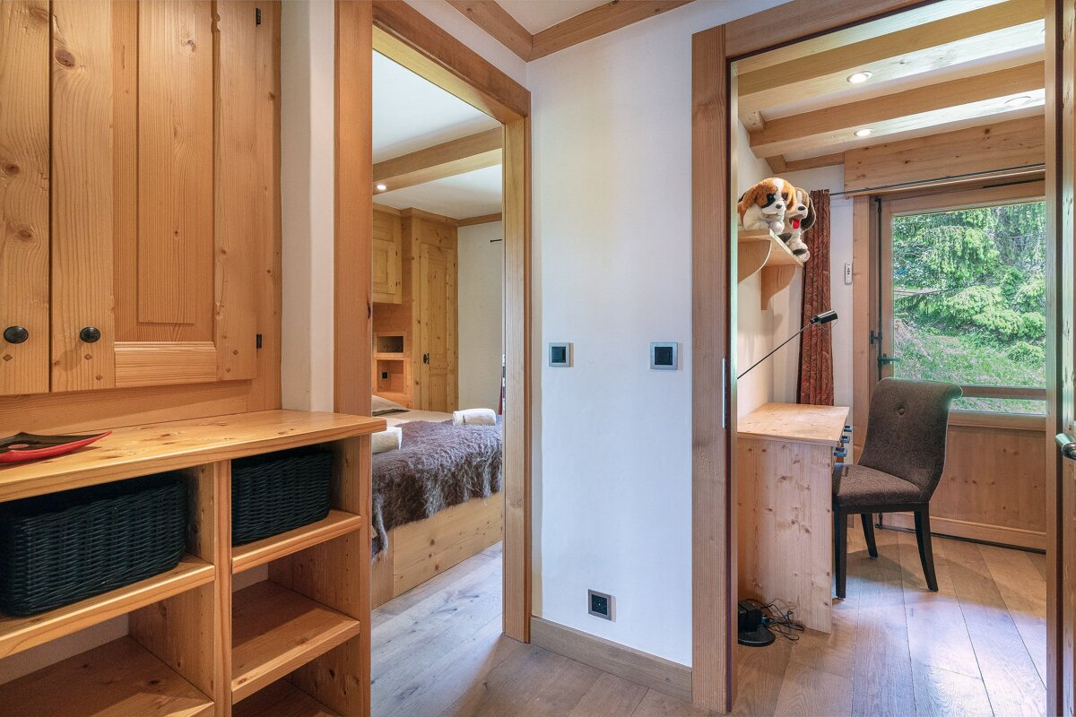 A hallway leading to a bedroom with a desk and chair