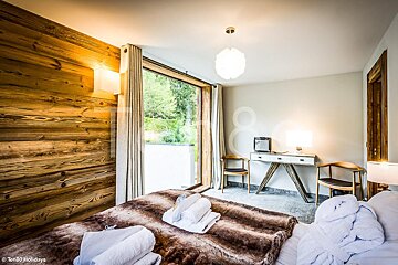 A bedroom with a wooden wall and a large window