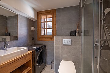 A bathroom with a washing machine and a toilet