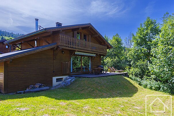 A large wooden house with a balcony surrounded by trees