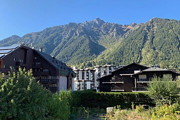 A view of a mountain range with a few buildings in the foreground