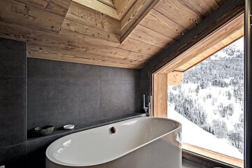 A bathtub in a bathroom with a view of snowy mountains
