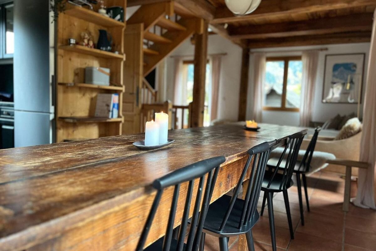 A wooden table with black chairs and a candle on it