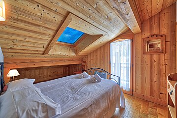 A bedroom with a skylight above the bed