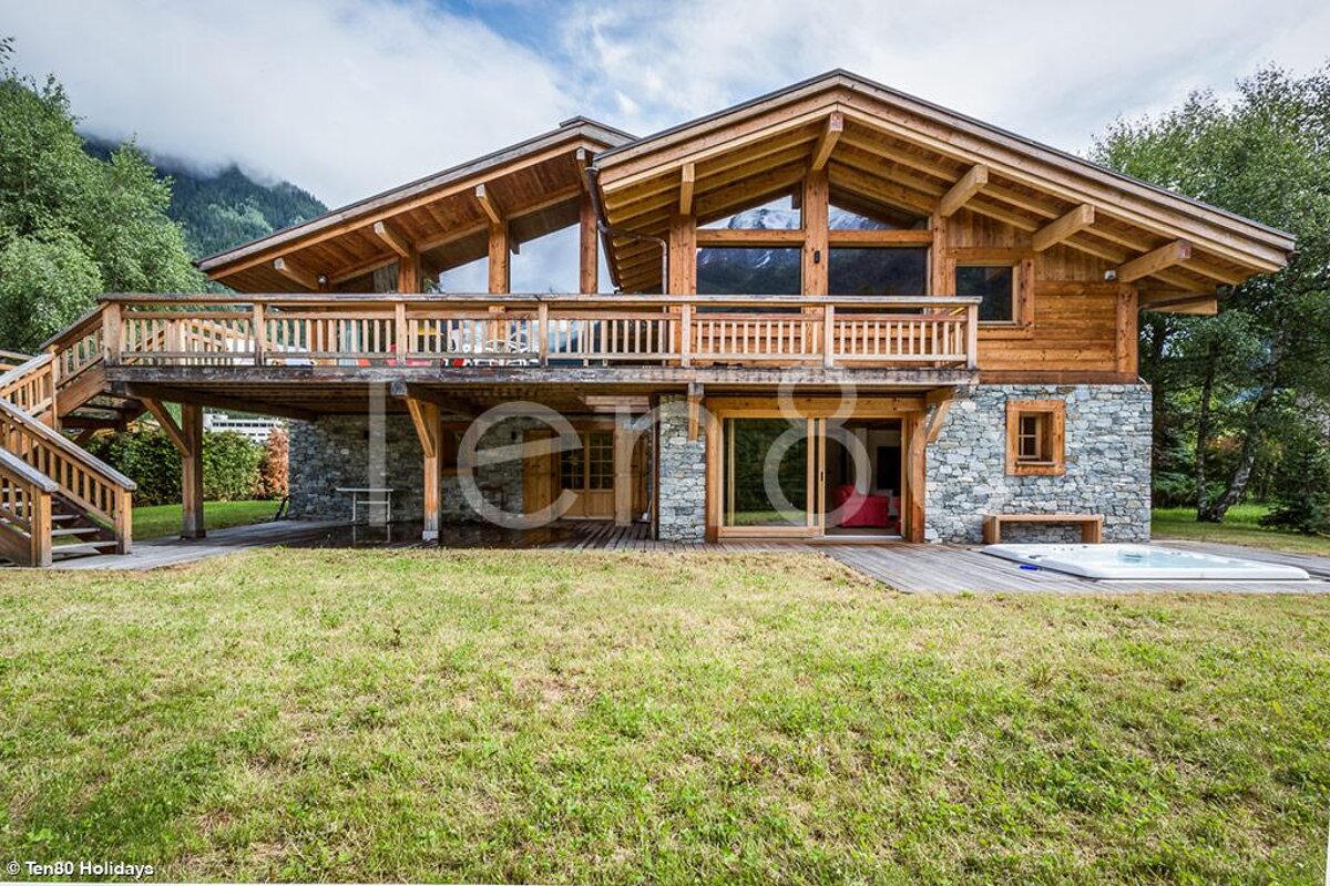 A large wooden house with a hot tub in front of it