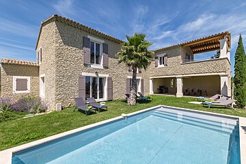 A large stone house with a swimming pool in front of it