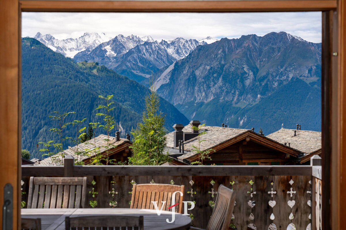 A view of a mountain range from a balcony with a vjp logo