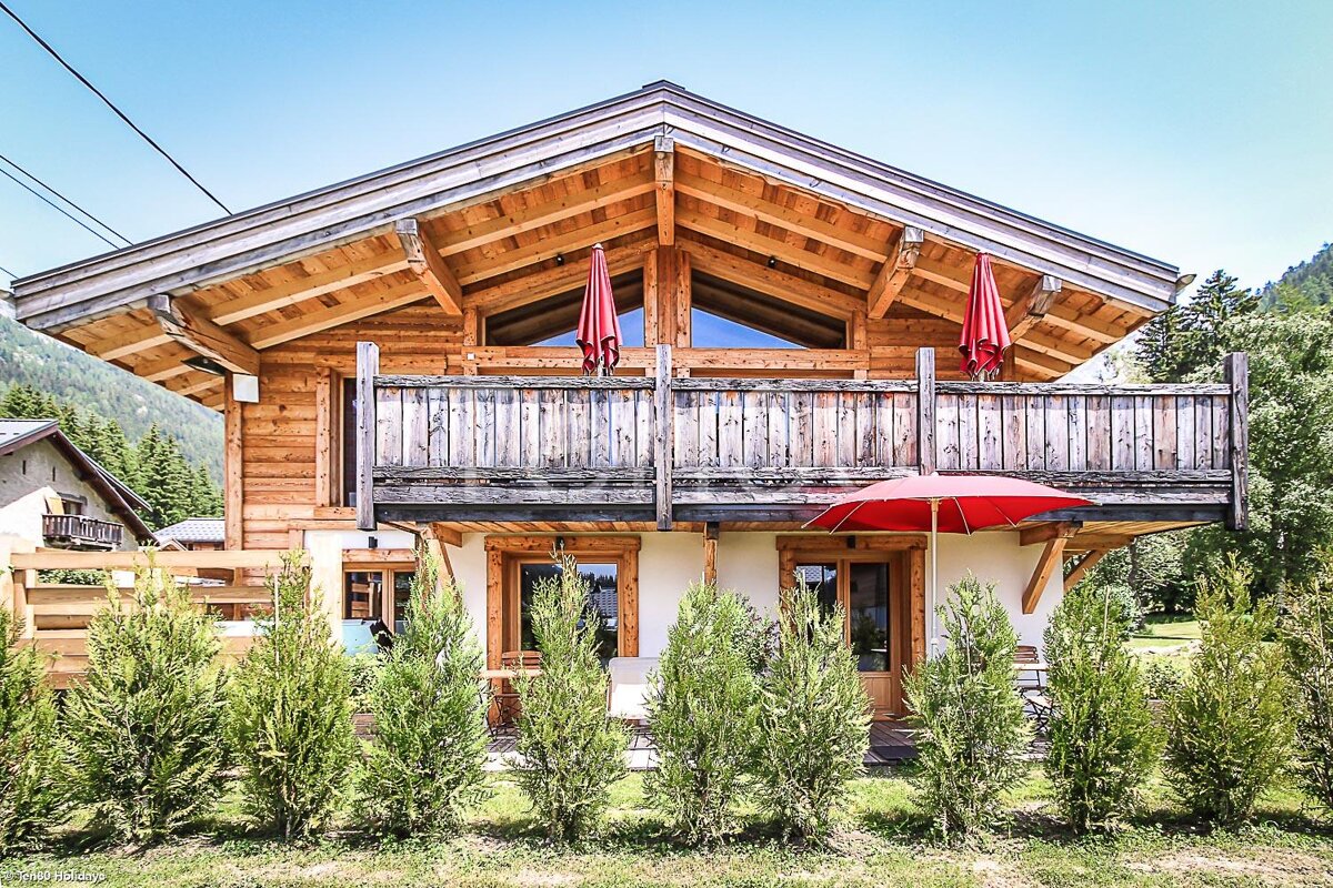 A wooden house with a red umbrella on the balcony