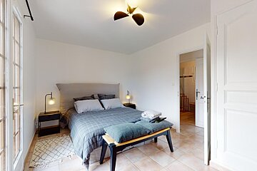 A bedroom with a large bed and a ceiling fan