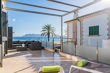 A balcony with a view of the ocean and palm trees