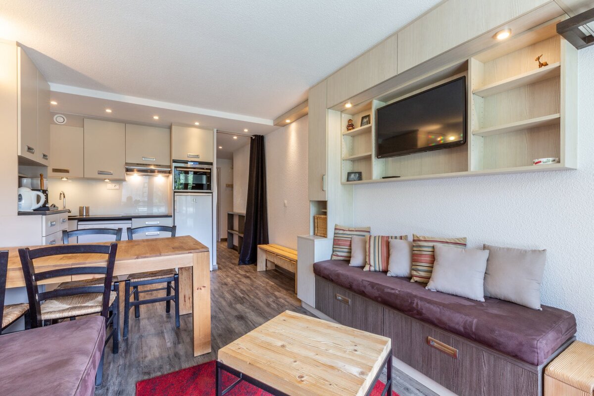 A living room with a table and chairs and a flat screen tv