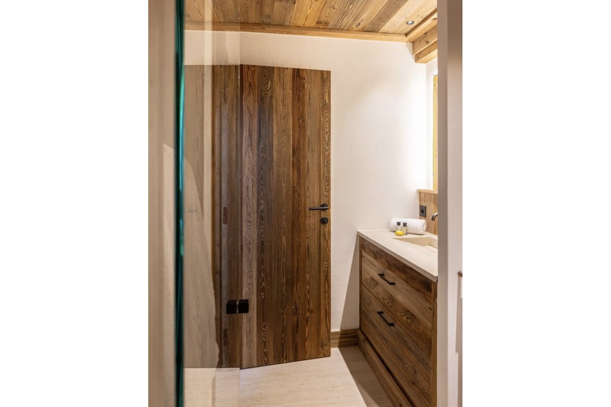 A bathroom with a wooden door and a sink