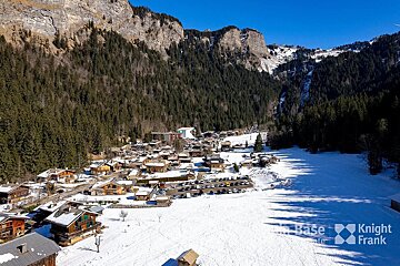 An aerial view of a snowy mountain village taken by knight frank