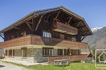A large wooden house with a picnic table in front of it