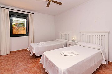 A bedroom with two beds and a ceiling fan
