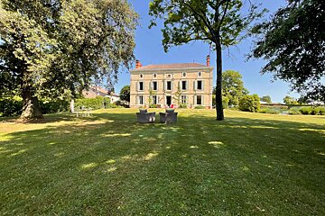 A large house sits in the middle of a lush green field