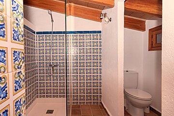 A bathroom with blue and yellow tiles and a toilet