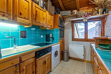 A kitchen with wooden cabinets and a washer and dryer