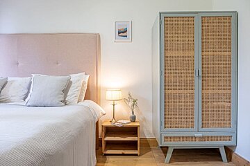 A bedroom with a bed and a wicker wardrobe