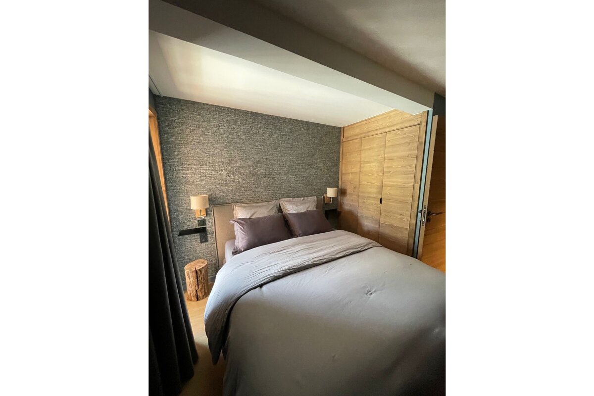 A bedroom with a bed and two lamps on the wall