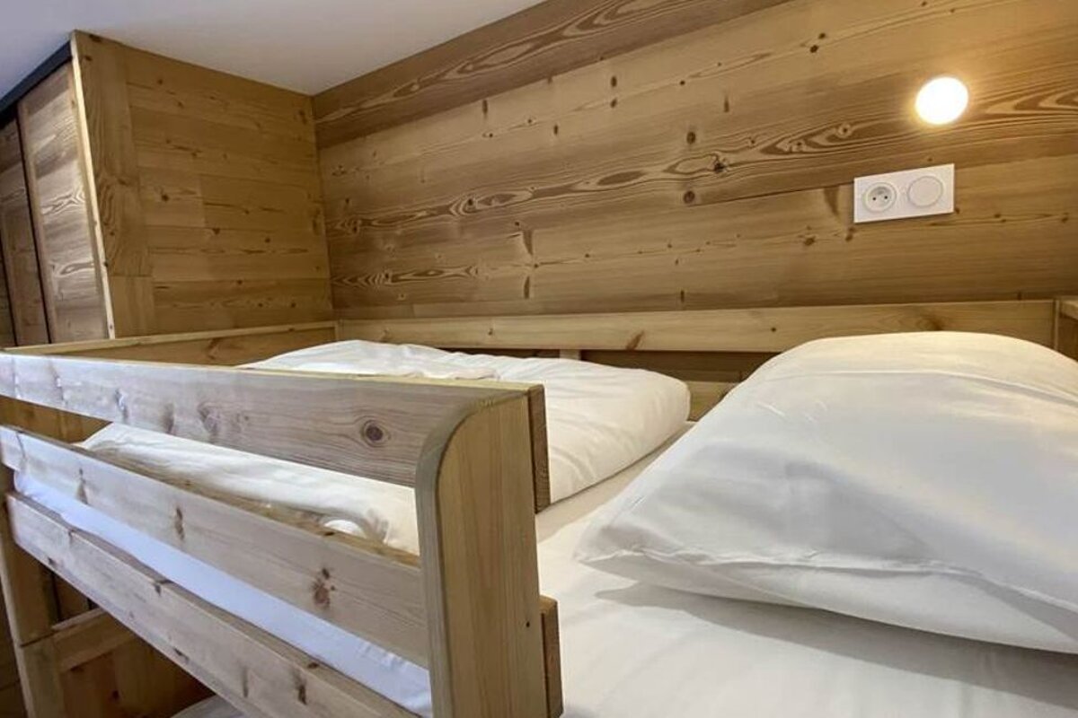 A wooden bunk bed with white sheets and pillows