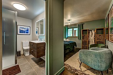 A bathroom with a toilet a sink and a chair
