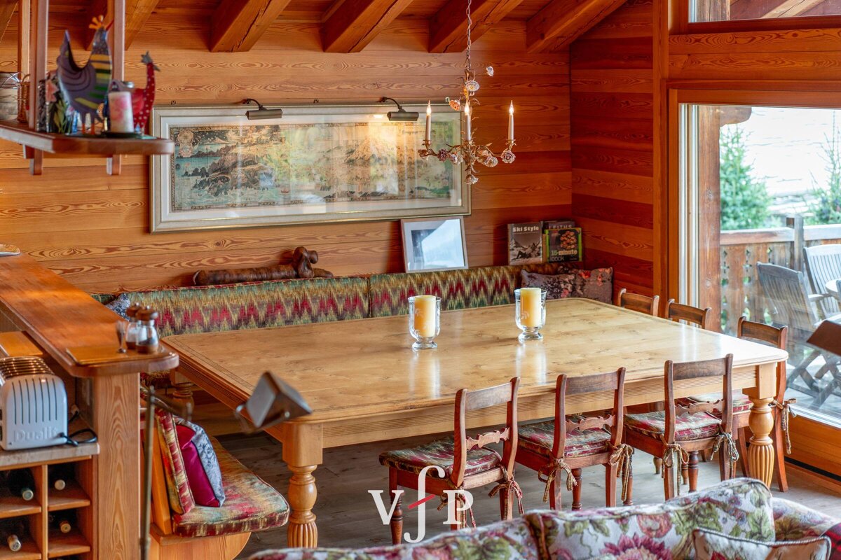 A wooden dining room with a table and chairs and a book titled 