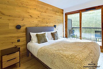 A bedroom with a large bed and a white management logo