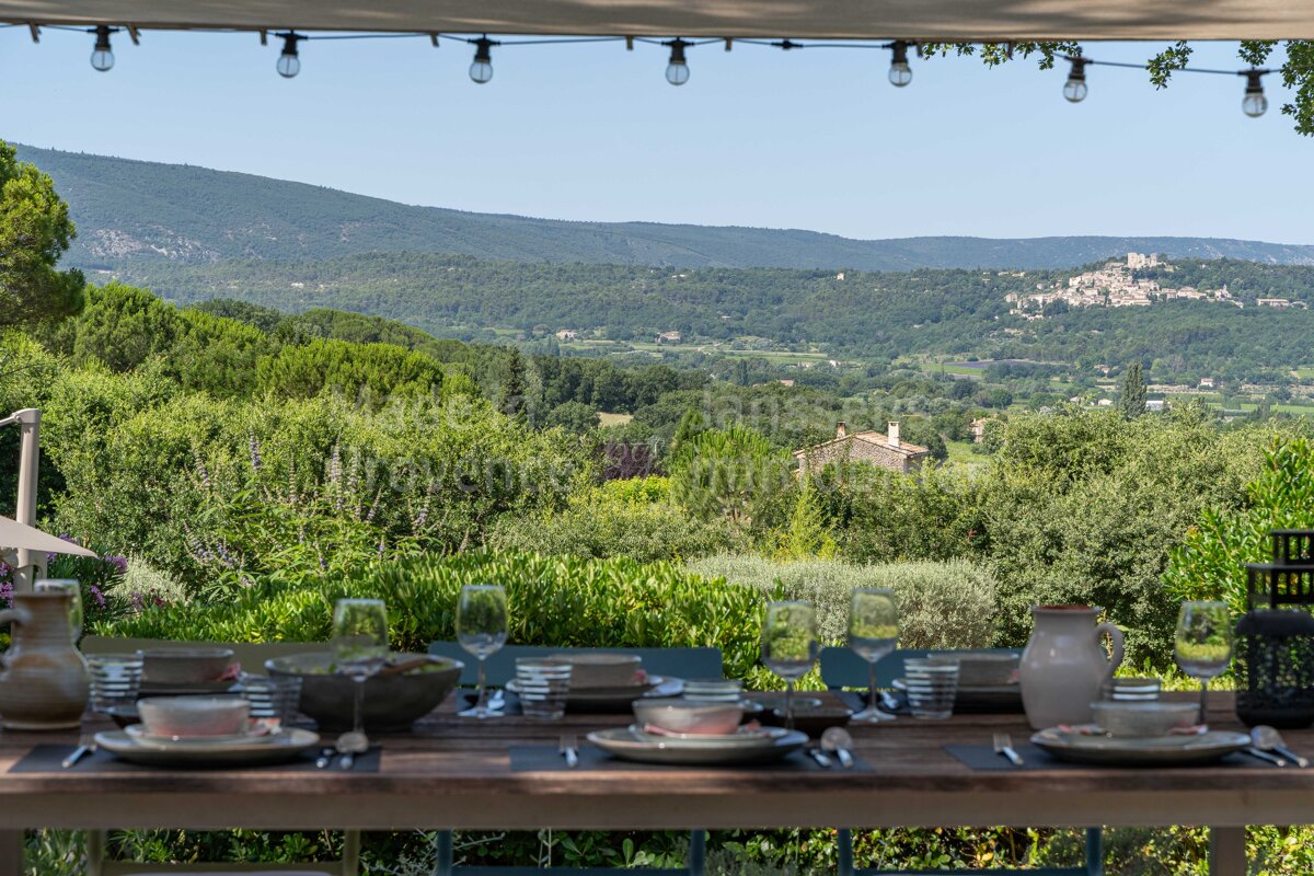 A table set with plates and glasses with a view of mountains in the background