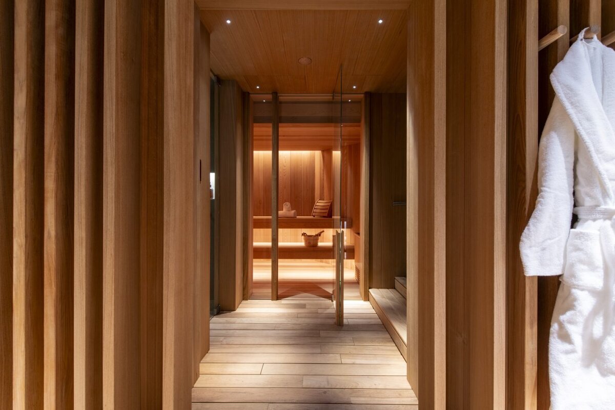A white robe hangs in a wooden hallway leading to a sauna