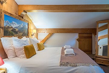 A bedroom with a painting on the wall above the bed
