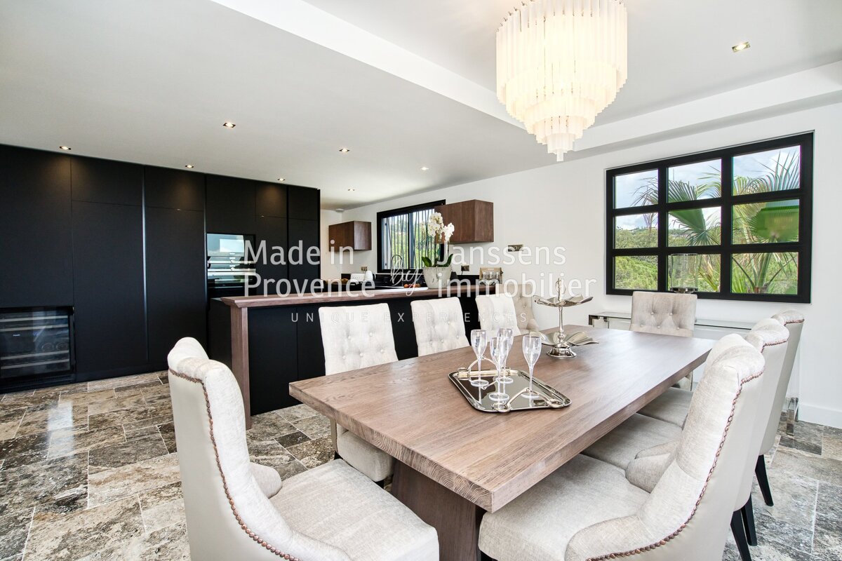 A dining room with a table and chairs and a sign that says madein janssens provence immobilier