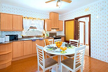 A kitchen with a table and chairs and a ceiling fan