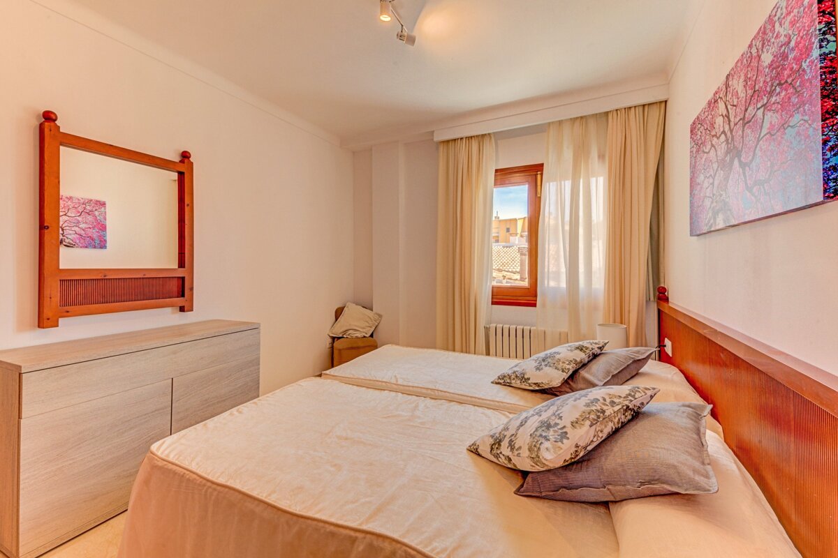 A bedroom with two beds and a mirror on the wall