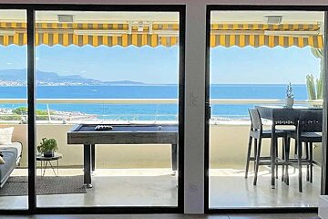 A pool table sits on a balcony overlooking the ocean
