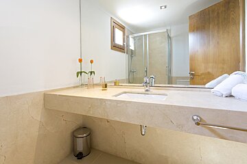 A bathroom with a sink a mirror and a trash can