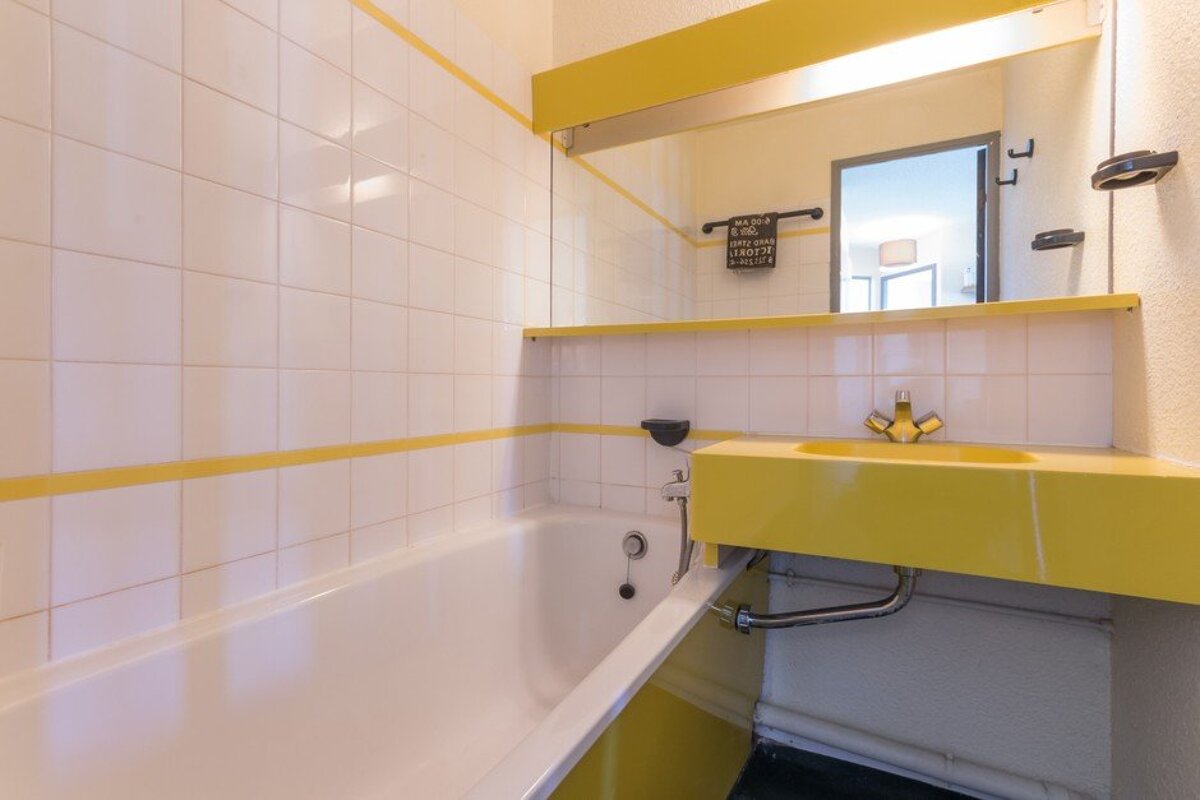 A bathroom with a yellow sink and white tiles