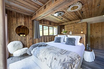 A bedroom with a large bed and a chair