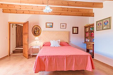 A bedroom with a pink bed and a bookshelf