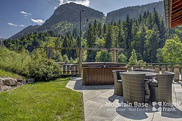 A hot tub sits on a patio with a mountain in the background