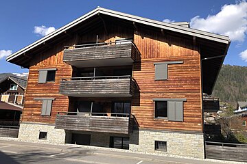 A wooden building with balconies and shutters on the windows