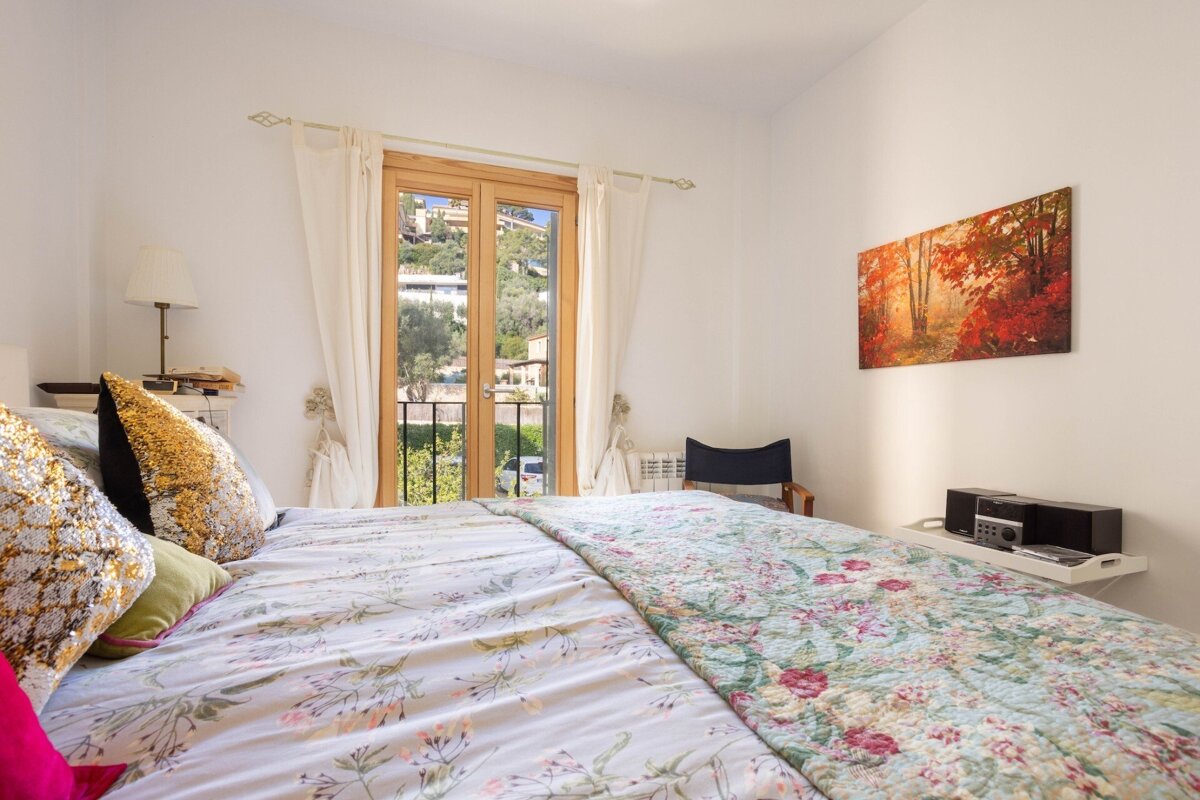 A bedroom with a painting on the wall above the bed