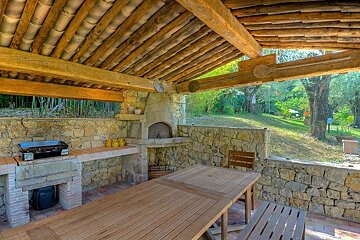 A wooden table and chairs under a wooden roof