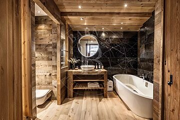 Chalet-style bathroom with light wood walls/floor, black marble accents, a modern tub, wooden vanity with a vessel sink, and a backlit mirror.
