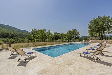 A large swimming pool surrounded by lawn chairs and umbrellas