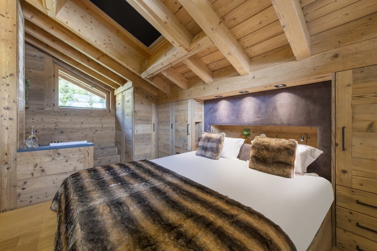A bed with a fur blanket and pillows in a wooden room