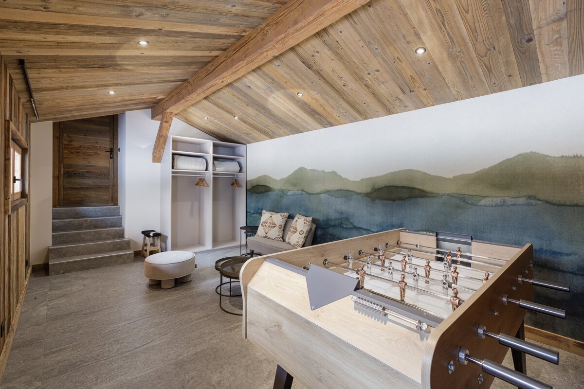 A foosball table in a room with a painting of mountains on the wall