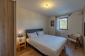 A bedroom with a large bed and a chair