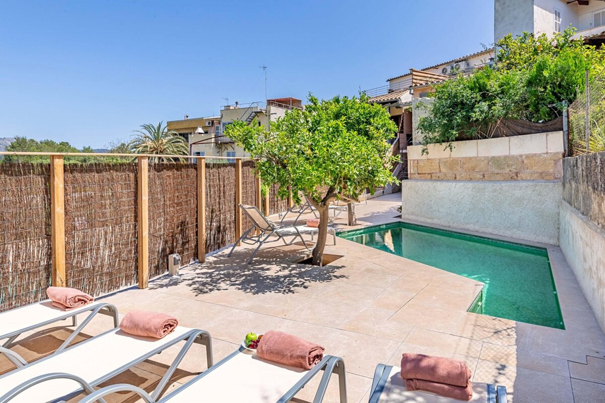A swimming pool is surrounded by chairs and a tree