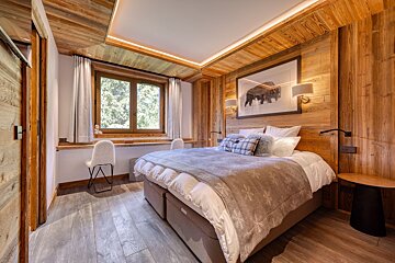 A bedroom with a large bed and a picture of a bear on the wall